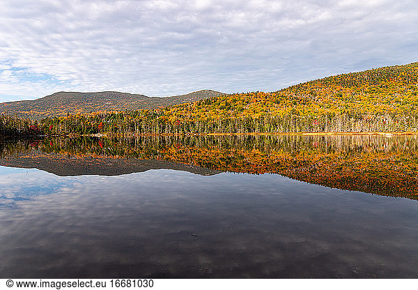 Colorful trees in the White Mountains reflecting in calm lake water.