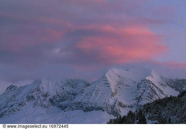 colour clouds between mountains in a snowy landscape at sunset