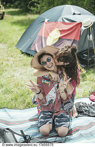 colourful queer female couple hug outside tent in summer camp