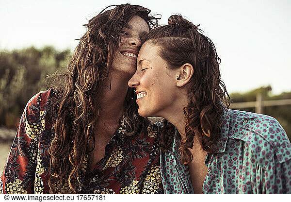 colourful queer women couple smile and play affectionately on vacation