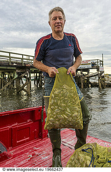 Commercial clammer Joe Delano holds freshly harvested clams at Pine Point in Scarborough  Maine.