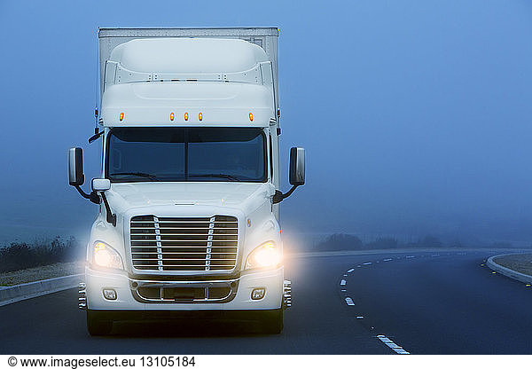 Commercial Class 8 truck being driven in the fog on a country road.
