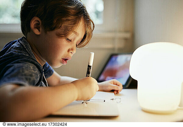 Concentrated boy drawing with felt tip pen at home