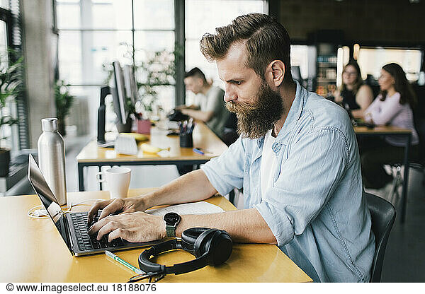 Concentrated male programmer typing on laptop while working in startup company