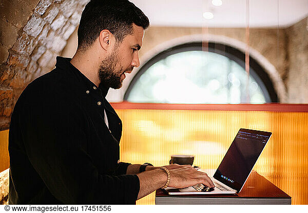 Concentrated man using laptop computer at cafe