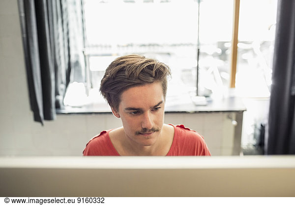 Concentrated young businessman using computer in new office