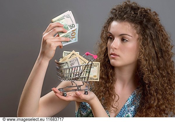 Concept of the cost of living a woman with serious expression holding supermarket trolley full of cash