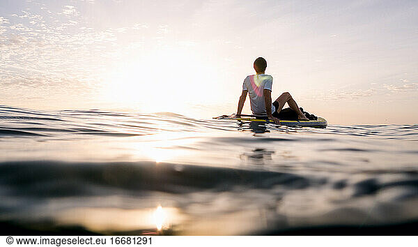 Concept: tranquility and relaxation. Man sitting on paddle surf
