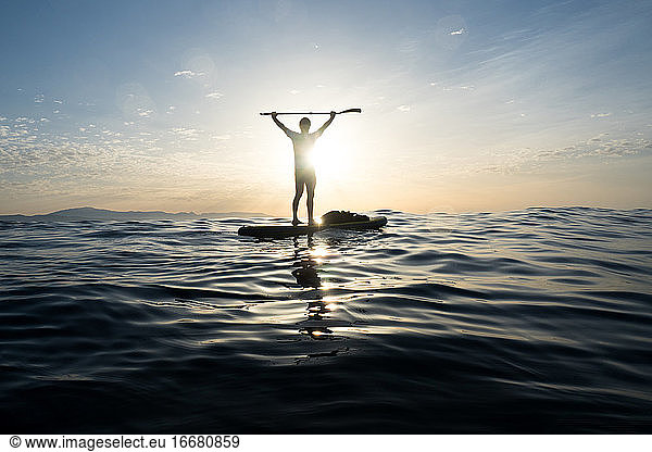 Concept: Victory and happiness. Man on a paddle surf board. In t