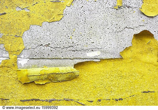 Concrete wall with canary yellow  orange peeling paint old cracked damaged rough bright background texture closeup.