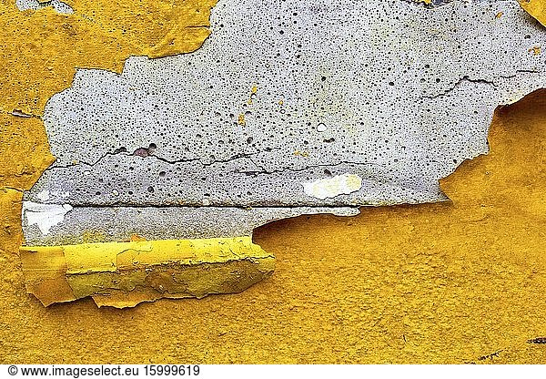 Concrete wall with yellow  orange peeling paint old cracked damaged rough bright background texture.