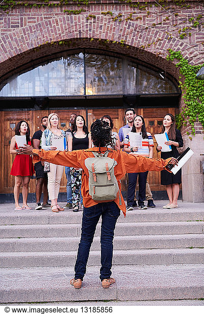Conductor directing choir outside language school