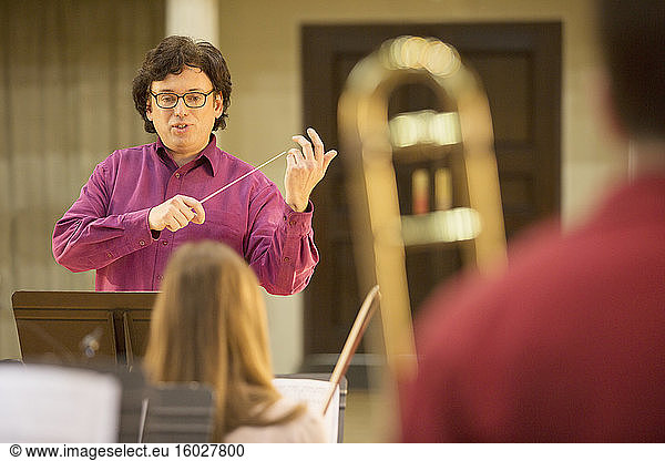 Conductor leading orchestra in practice