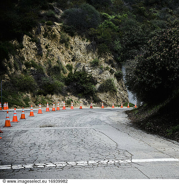 Cones on rural highway with cracked asphalt.