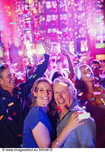 Confetti falling on smiling mature people dancing in nightclub