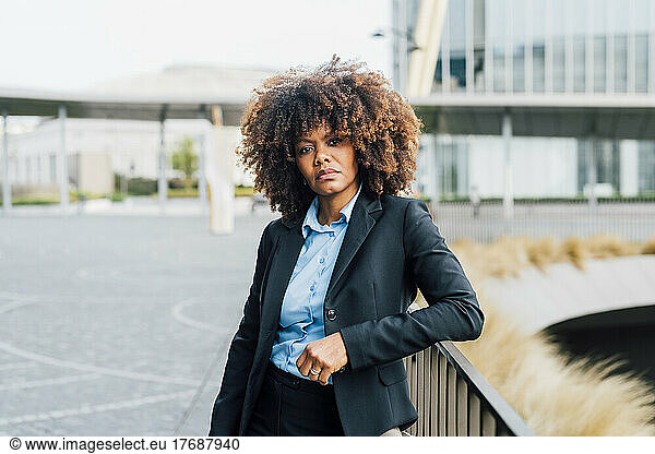 Confident Afro businesswoman standing by railing