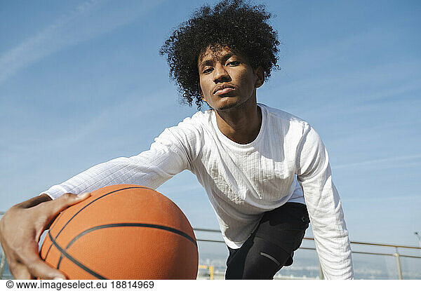 Confident athlete with curly hair playing basketball