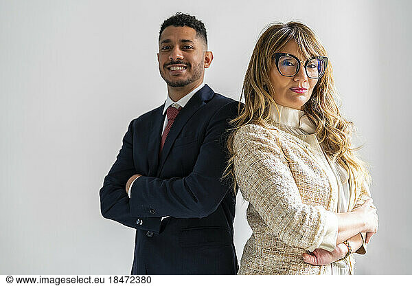 Confident business partners standing with arms crossed against white background