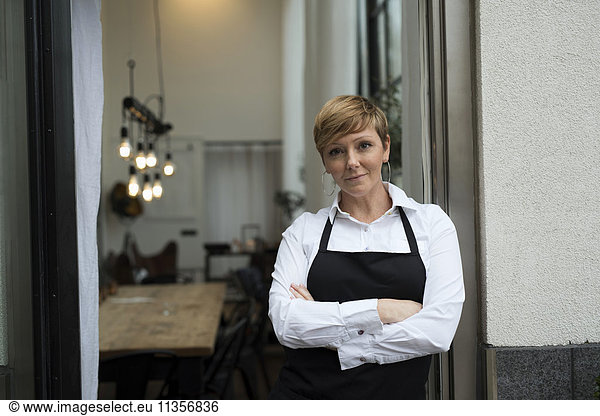 Confident business professional standing with arms crossed against workshop