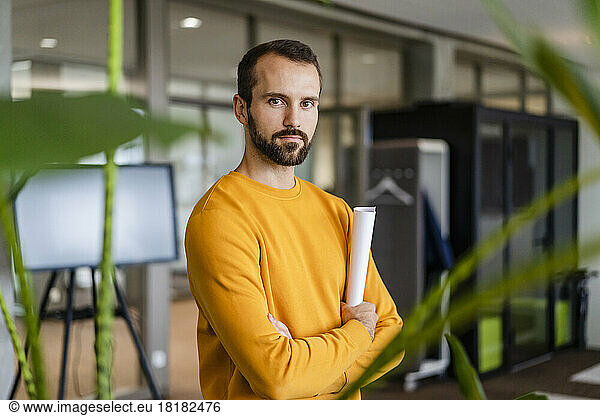 Confident businessman holding document at workplace