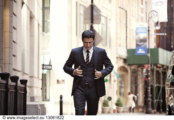 Confident businessman looking down while walking on city street