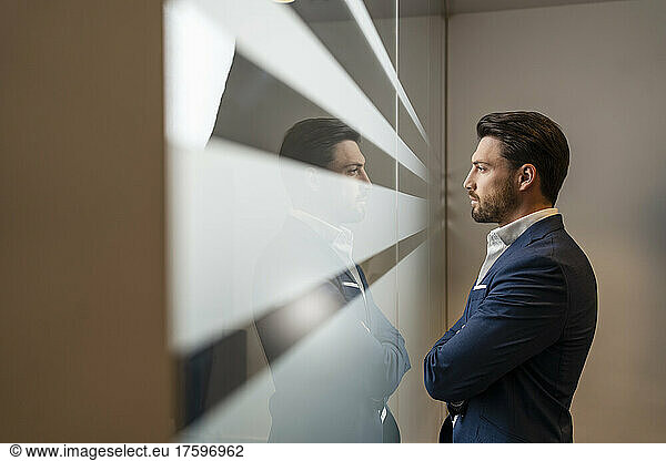 Confident businessman looking through window in office