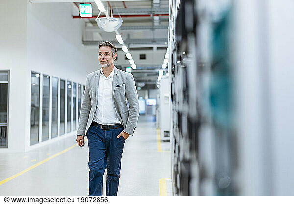 Confident businessman walking in a modern factory