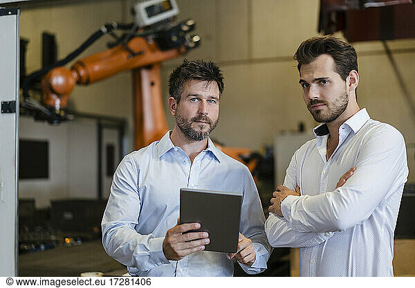 Confident businessmen using digital tablet while standing at factory