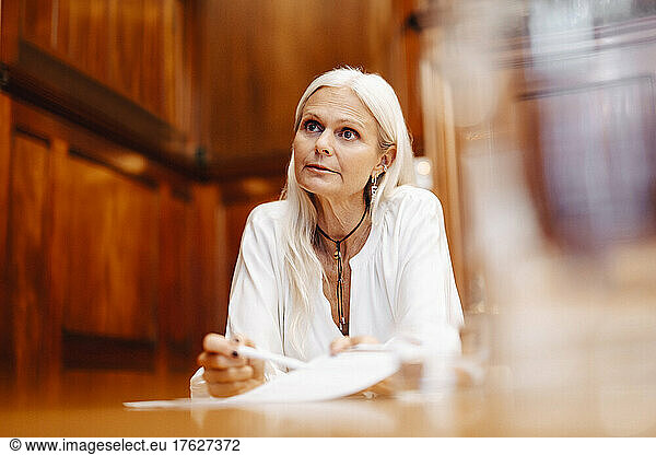 Confident businesswoman sitting with contract document in board room