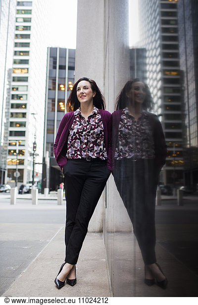 Confident businesswoman standing on sidewalk by glass window