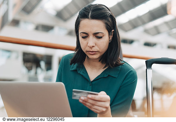 Confident businesswoman with laptop and credit card in airport