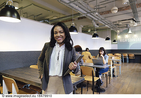 Confident businesswoman with laptop standing at office