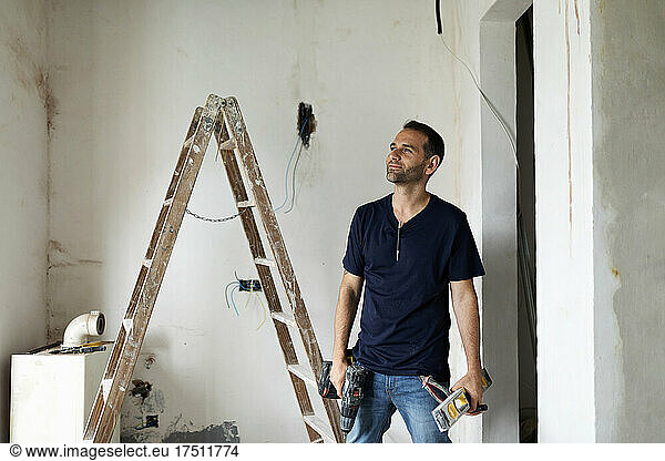Confident construction worker standing in a house under construction