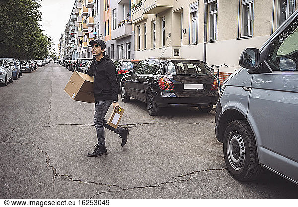 Confident delivery man with package walking on street in city