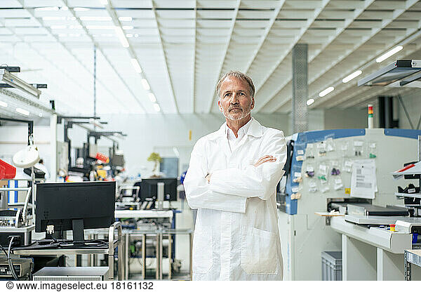 Confident engineer with arms crossed standing at industry