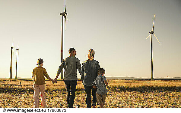 Confident family walking through wind park holding hands