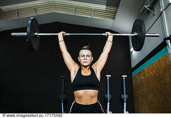 Confident female athlete lifting deadlift in gym