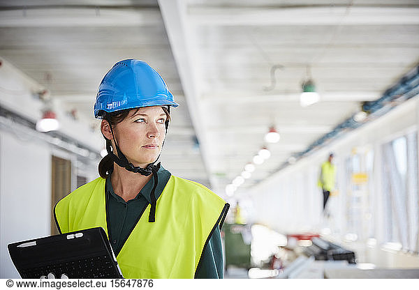 Confident female construction manager in reflective clothing looking away
