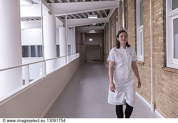 Confident female doctor looking away while walking in hospital corridor