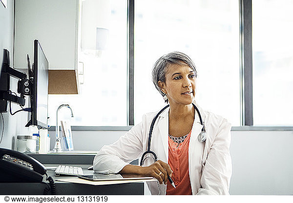 Confident female doctor sitting at desk in clinic
