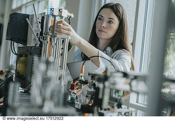 Confident female engineer inventing machinery in laboratory