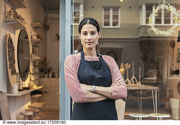 Confident female owner with arms crossed outside store