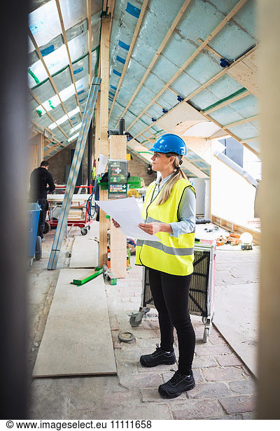 Confident female worker analyzing document while standing at construction site