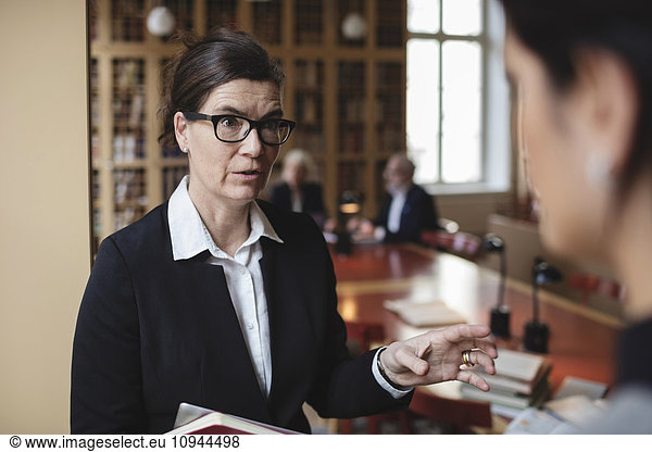Confident lawyer discussing with female colleague in library