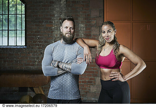 Confident male and female fitness instructors in gym