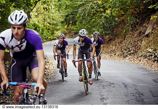 Confident male athletes riding bicycles on road
