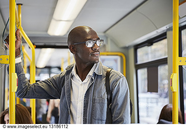 Confident male commuter looking away while standing in tram