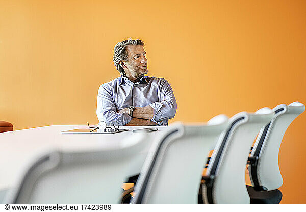 Confident male professional sitting with arms crossed inboard room