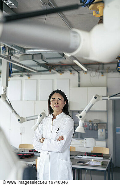 Confident scientist standing with arms crossed in laboratory