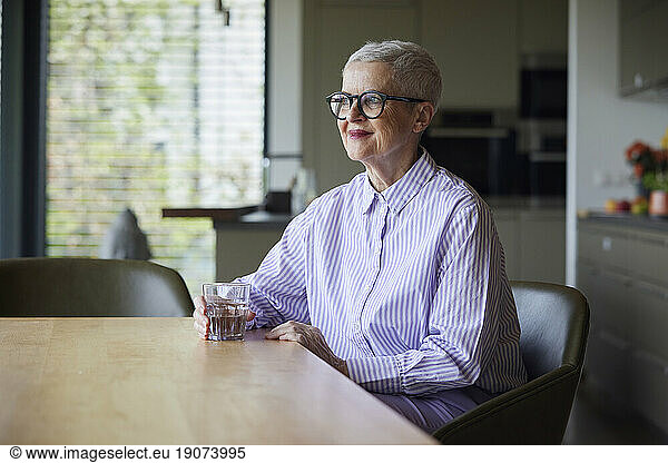 Confident senior woman sitting at table at home